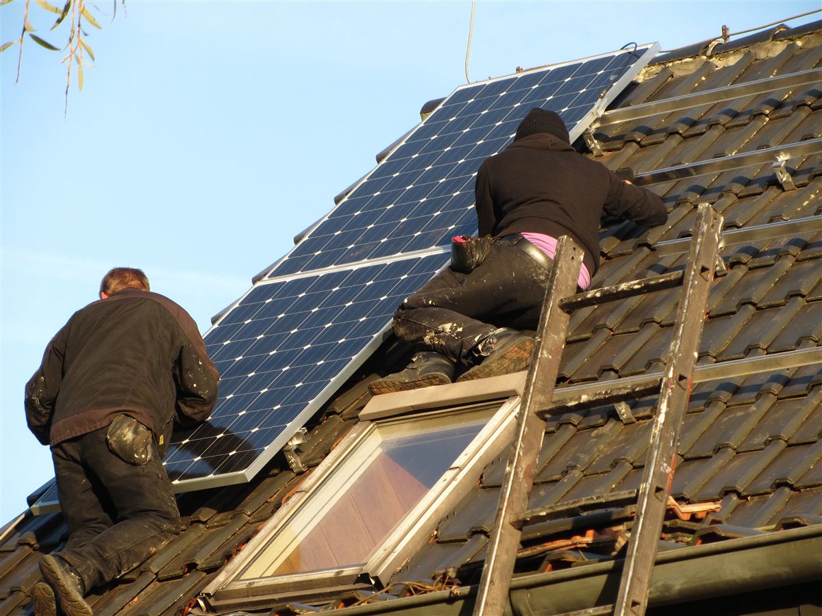 Handwerker installieren Photovoltaik-Module auf einem Hausdach